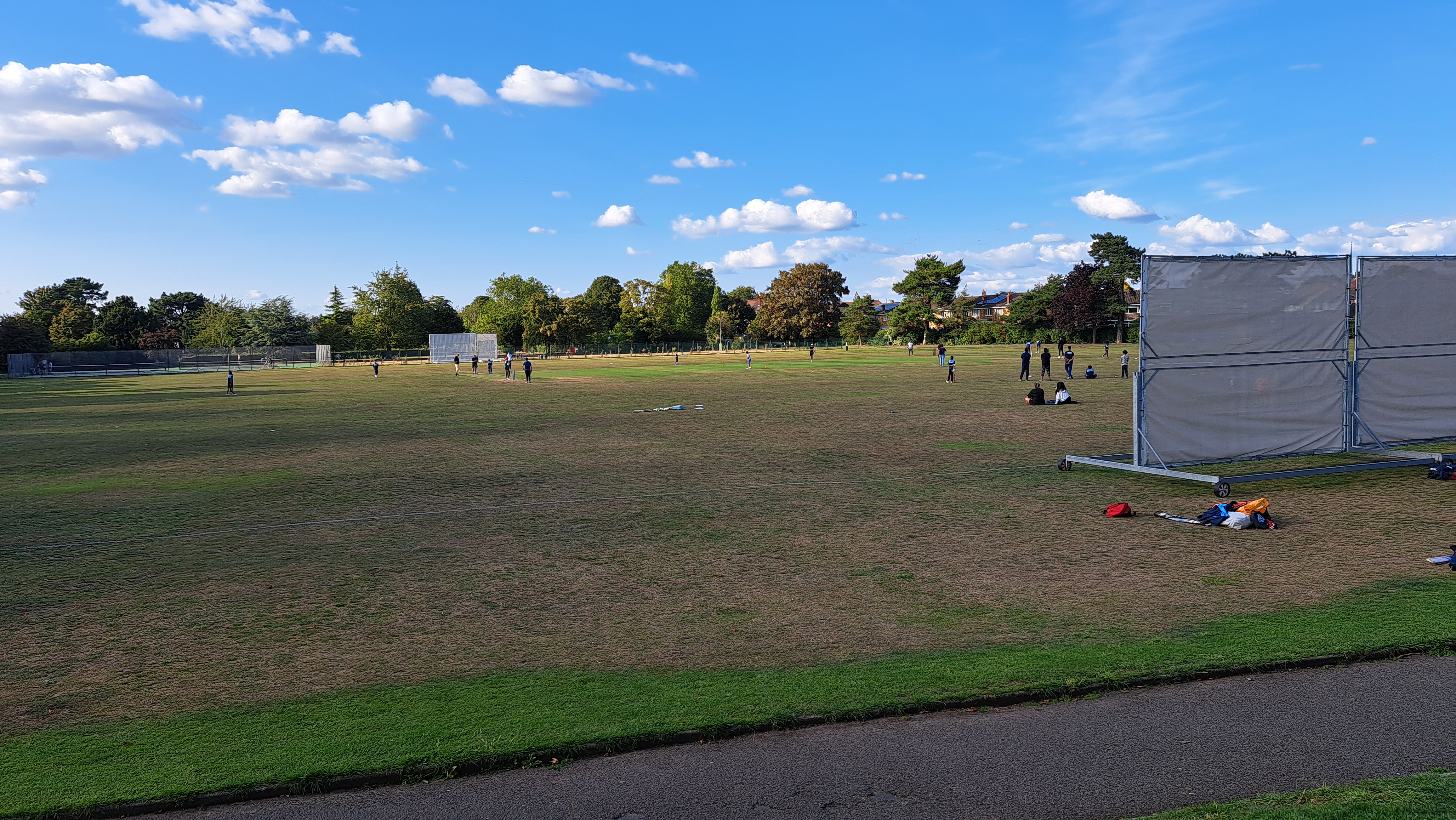 Hesketh Park cricket ground showing the outfield and square with practice session in progress under blue skies